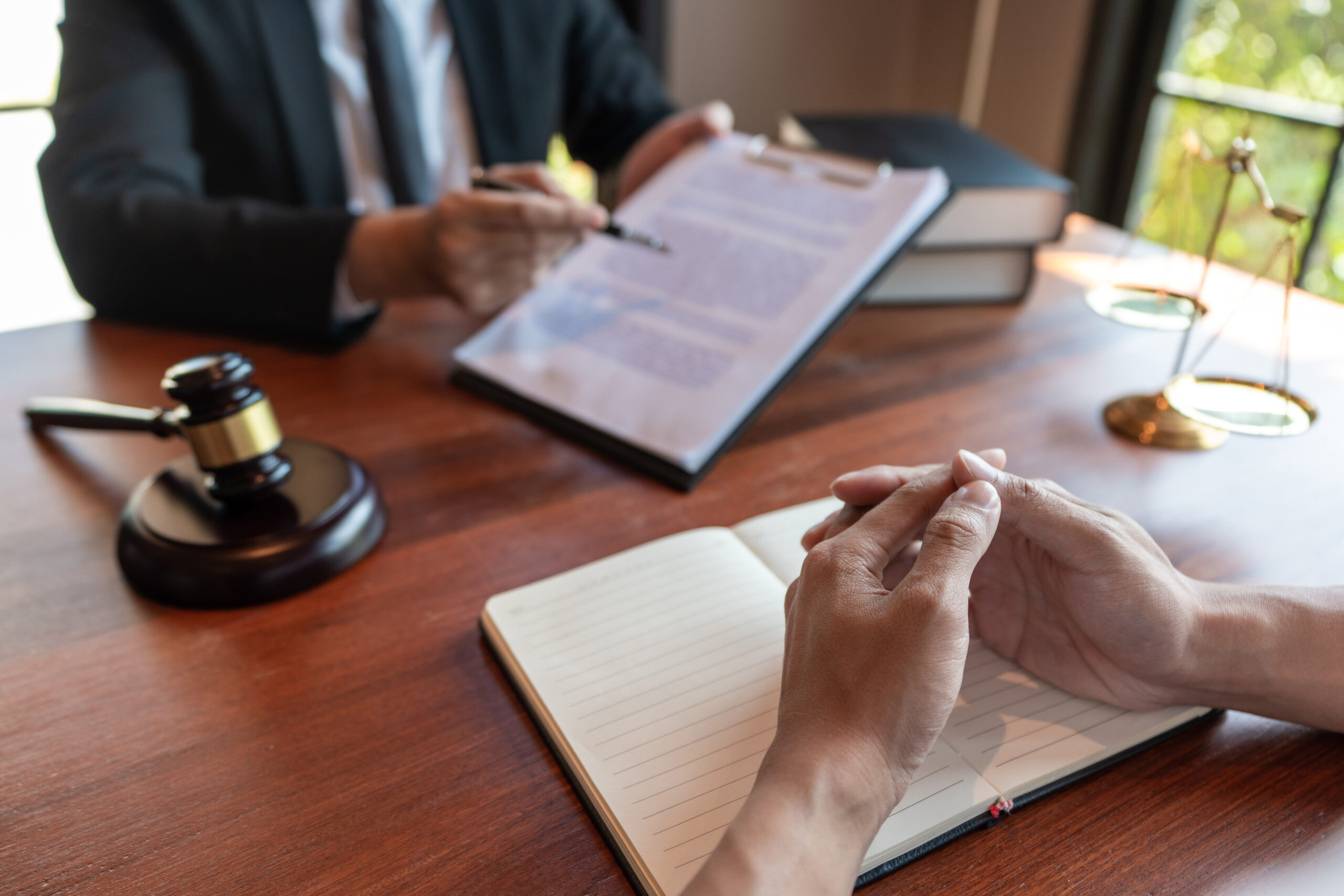Lawyer working with client discussing contract papers with brass scale about legal legislation in courtroom, consulting to help their customer.